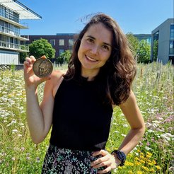 Lea Dietrich holds the Otto Hahn Medal at the flower meadow of the Max Planck Insititute of Biophysis